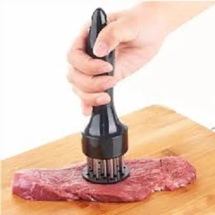Stainless steel needle meat tenderizer being pressed into a fresh raw beef steak